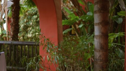 Outdoor tropical resort scene with lush greenery and vibrant architecture, featuring blurred foliage and defocused elements creating a serene luxury ambiance.