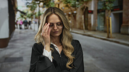 Blonde woman in judge uniform stands confidently outdoors on a city street conveying authority and...