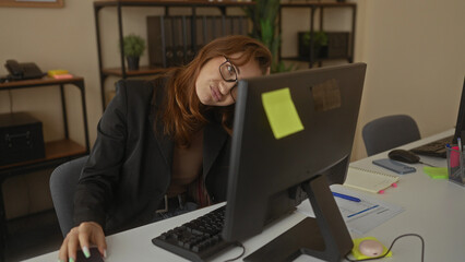 Caucasian woman in office looking stressed with computer and phone surrounded by work materials...