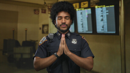 Police officer wearing uniform meditating calmly at an airport terminal with blurred departure...
