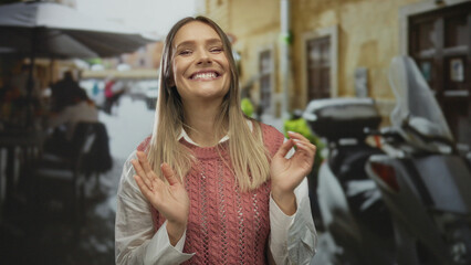 Woman clapping on a city terrace at an outdoor restaurant cafe, smiling amid urban street scene in...