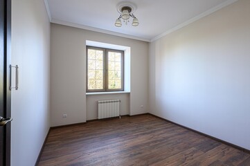 empty room with wood floors, light beige walls, a window, and a light fixture. It appears clean and bright