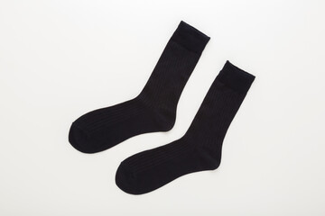 Two new dark black long male socks on light gray table background. Closeup. Top down view.
