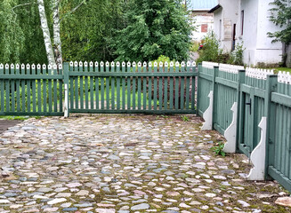 A neatly manicured farmyard, cobbled and enclosed by a wooden fence