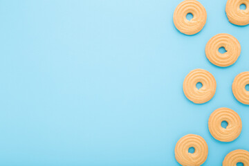 Circle shape of dry cookies on light blue table background. Pastel color. Closeup. Sweet snack. Empty place for text. Top down view.