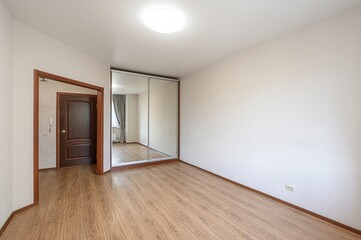 empty room with wooden floors, a sliding-door mirrored wardrobe, and a partially open door. The...