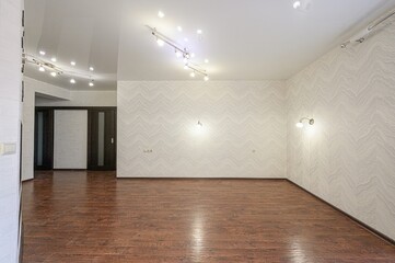 Empty room featuring wooden floors, patterned wallpaper, a glossy ceiling, and track lighting