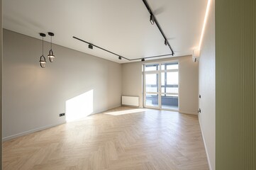 Bright room with herringbone floor, track lighting, and large windows. Minimalist design with...