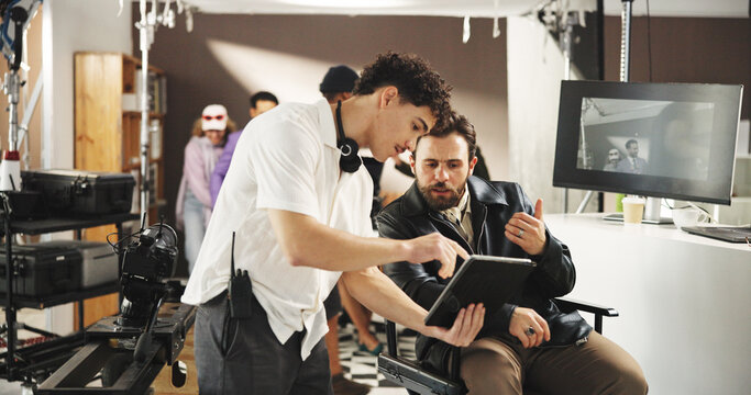 Man, director and producer with tablet for discussion, video edit or retake in production studio. Male people, filmaker and talking with camera assistant or technology for film making or scene cue - Powered by Adobe