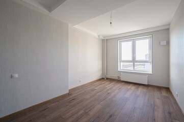 bright, empty room with wood floors, light grey walls, and a large window