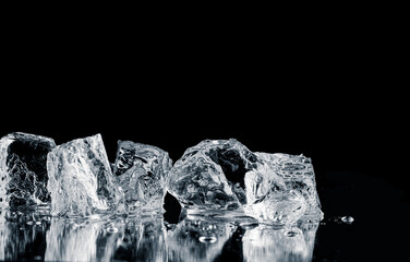 Natural ice cubes, melting on a black reflective surface.