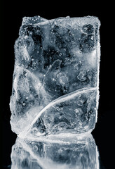 Textured natural ice block with cracks, on a black background with reflection. A melting piece of...
