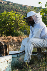Beekeeper sitting and resting after taking care of bees in countryside