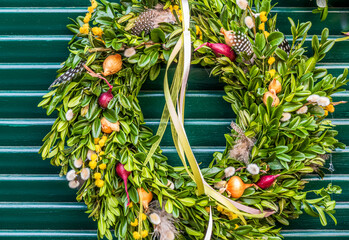 Decorative wreath hangs on vibrant green and red wooden wall in quaint outdoor setting during the...