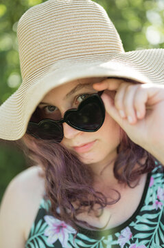 Young girl wearing heart shaped sunglasses and a hat, summer time