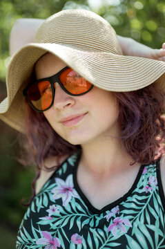 Young girl wearing orange sunglasses and a hat, summer holidays