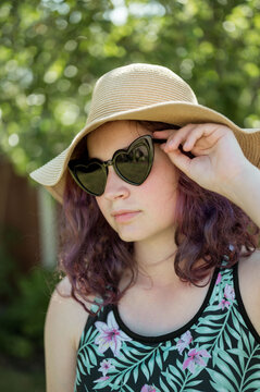Young girl wearing heart shaped sunglasses and a hat, summer holidays