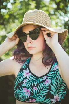 Young girl wearing heart shaped sunglasses and a hat, summer holidays