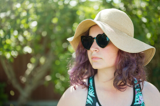 Young girl wearing heart shaped sunglasses and a hat, summer holidays