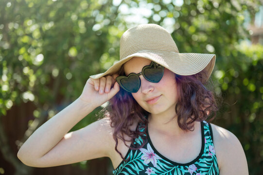Young girl wearing heart shaped sunglasses and a hat, summer holidays