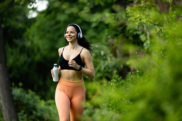 Fit and healthy fitness woman running in the park and enjoying and listening to music.
