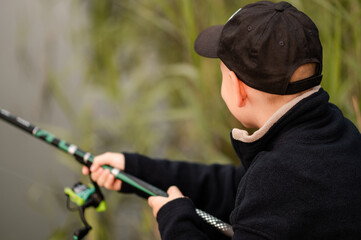 Close-up of a teenage boy fishing by a calm foggy lake in the early morning, fully focused and...