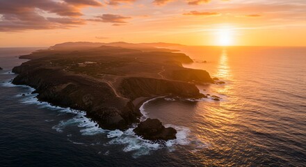 Aerial view of a rugged island coastline at sunset, with golden light reflecting on the ocean surface.