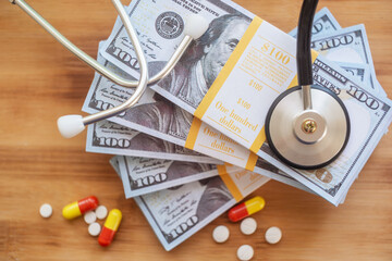 The image features a stack of hundred-dollar bills alongside a stethoscope and various prescription...