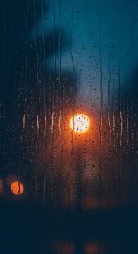 Rain-streaked window with blurred streetlights creating a warm, moody ambiance.