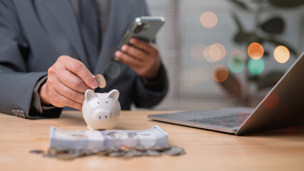 Focused Man In Suit Saving Money With Piggy Bank Coin, Financial Planning On Wooden Background With Dollar Bank Elements