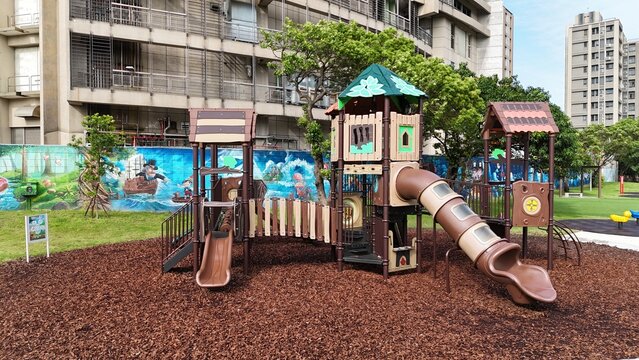 Forest-themed children’s playground equipment with mulch surface in urban park