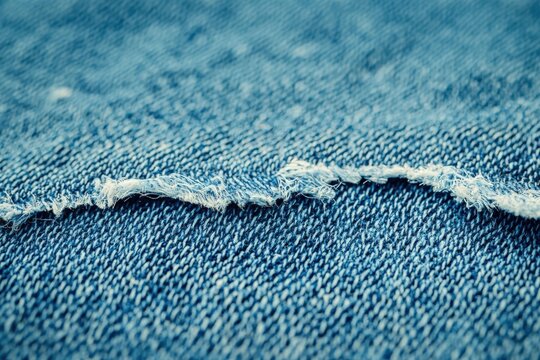 Close-up of distressed denim fabric with frayed edge