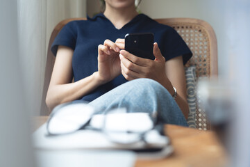 Woman using mobile phone and laptop checking email or news online while sitting at home. Searching...