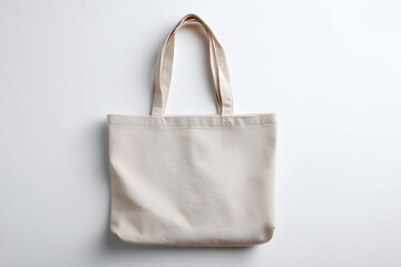 Folded beige canvas tote bag with handles, isolated on white. Eco-friendly shopping or branding concept.