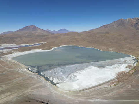 Aerial view of the tranquil lake reflecting the expansive sky surrounded by arid mountains, their peaks softened by distance, San Pablo de L&Atilde;&shy;pez, Potosi Department, Bolivia.