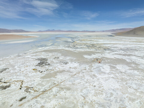 Aerial view of the stark white salt flats meeting the pale blue sky, a vast expanse under the sun's glare, San Pablo de L&Atilde;&shy;pez, Potosi Department, Bolivia.