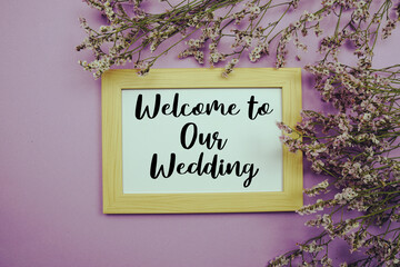 Welcome to Our Wedding text with flowers bouquet decoration on purple background