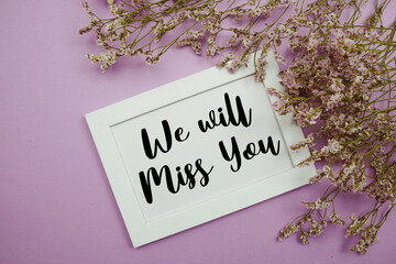 We will Miss You text with flowers bouquet decoration on purple background