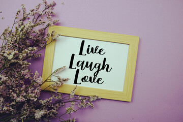 Live Laugh Love text with flowers bouquet decoration on purple background