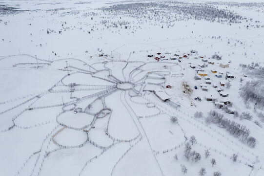 Aerial view of a snow-covered landscape with intricate reindeer herding fences radiating outwards like spokes from a central hub, Karigasniemi, Lapland, Finland.