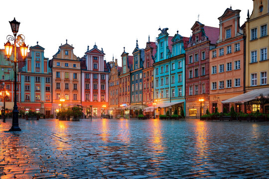 Old canal houses in Amsterdam and Gdansk reflecting in water under a clear sky