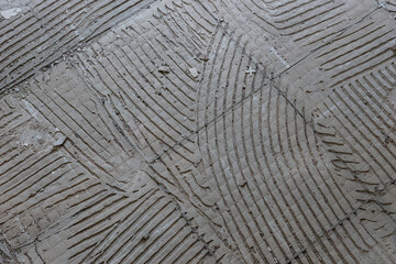Old hard tile adhesive on the floor. Abstract pattern of notched trowel