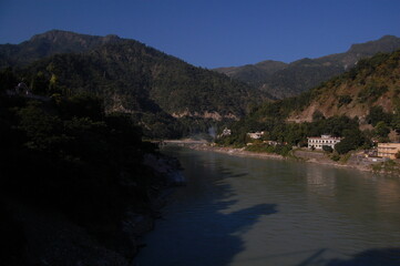 A serene landscape view of a river winding through mountains under a vast sky, reflecting the...