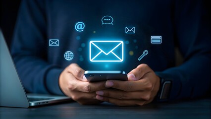 Person using a smartphone with glowing digital icons representing email communication social media and internet connectivity in a modern dark setting