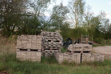 Pile of bricks and a tractor are in a field