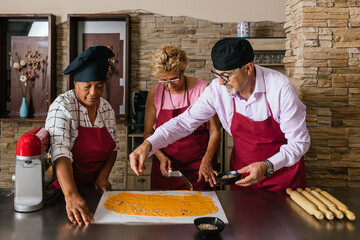 Chefs sprinkling seeds on dough during cooking class