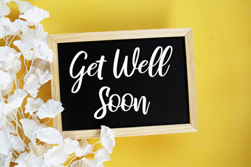 Get Well Soony text with flowers decoration on yellow background