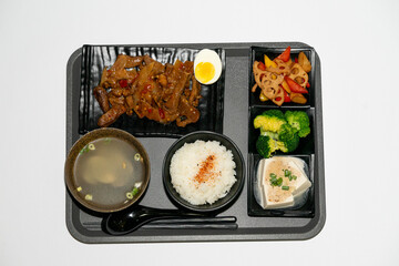 A well-balanced Asian-style set meal served on a tray, featuring tender braised beef strips (Hong Shao Niu Liu) as the main dish, accompanied by a bowl of steamed white rice, three assorted seasonal v