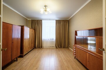 room with wood floors and vintage furniture. Gold curtains frame a bright window