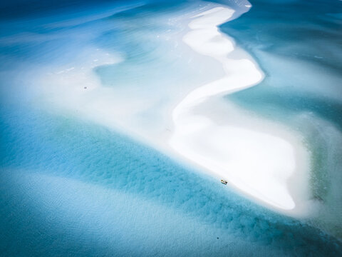 Aerial view of turquoise waters embracing a pristine sandbar, where the ocean's breath sculpts ephemeral landscapes of light and shadow, Queensland, Australia.